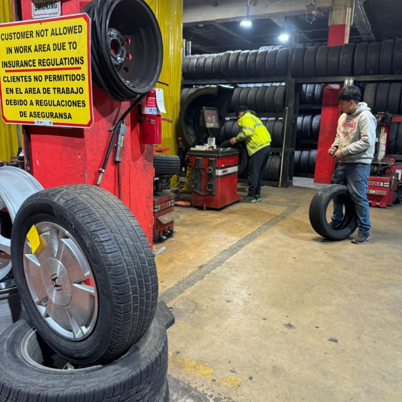 Technicians balancing a tire on a Coats machine inside the Hanover St shop