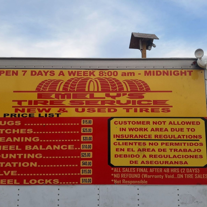 Emely's Tire Service price list signage close-up at North Point Blvd